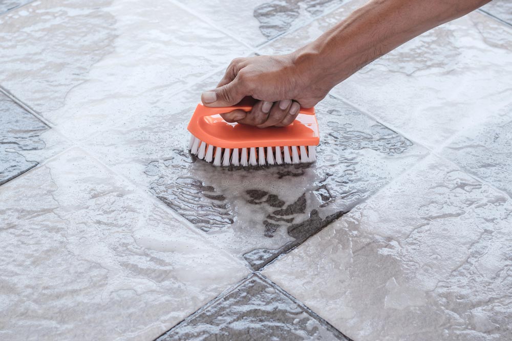 man using title floor cleaner to clean stone flooring
